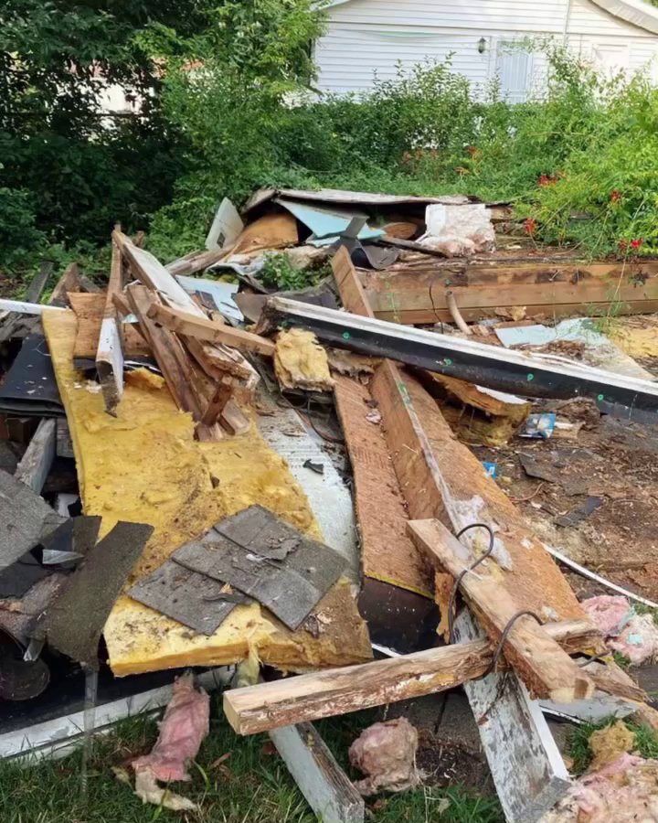 Two SQS Junk Removal workers in uniform standing in a cluttered garage, ready for a junk removal job in Charlotte, NC.