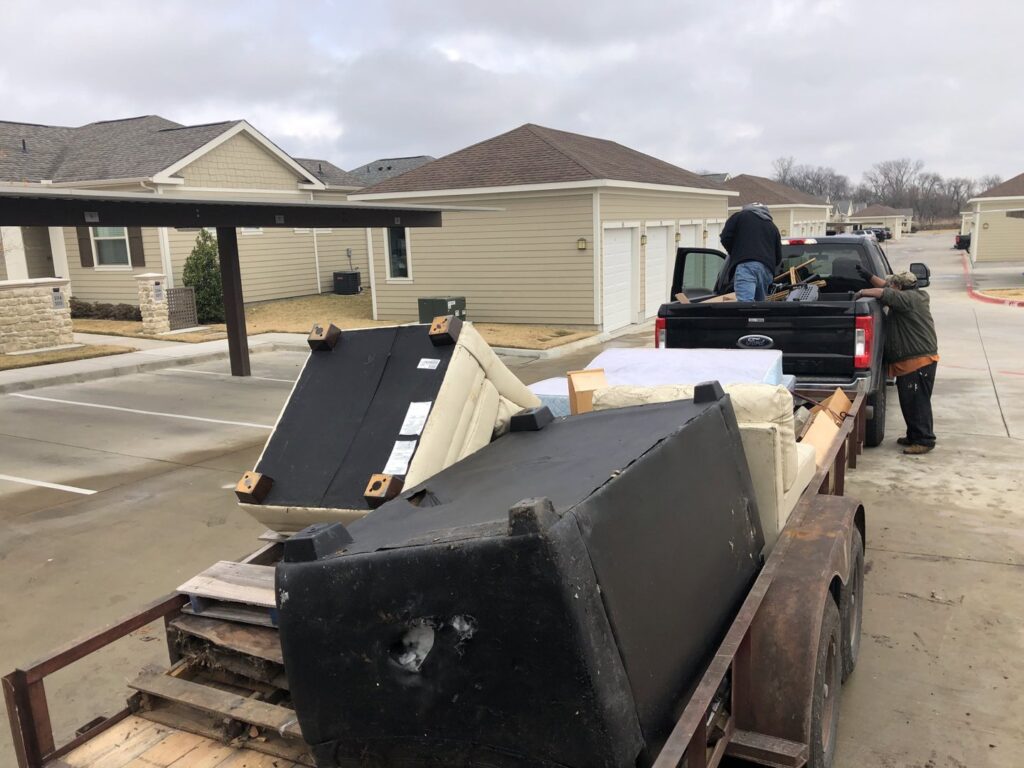 Workers loading sofas and mattresses onto a trailer for a junk removal job by Perez Junk Removal in Anaheim, CA.