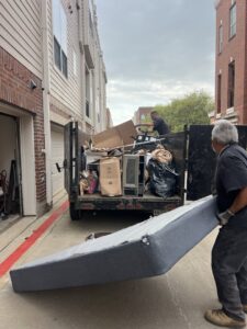 Lolo Hauling Junk Removal workers loading a mattress into a truck filled with other junk in Dallas, TX.