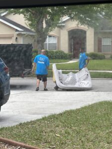 Two workers from Clean Tidy Places in Jacksonville, FL, removing a large hot tub for a professional junk removal service.