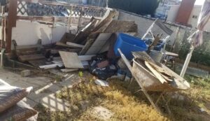 Two workers from Jake's Junk Removal carrying an old, worn-out couch down stairs for disposal in San Diego, CA.