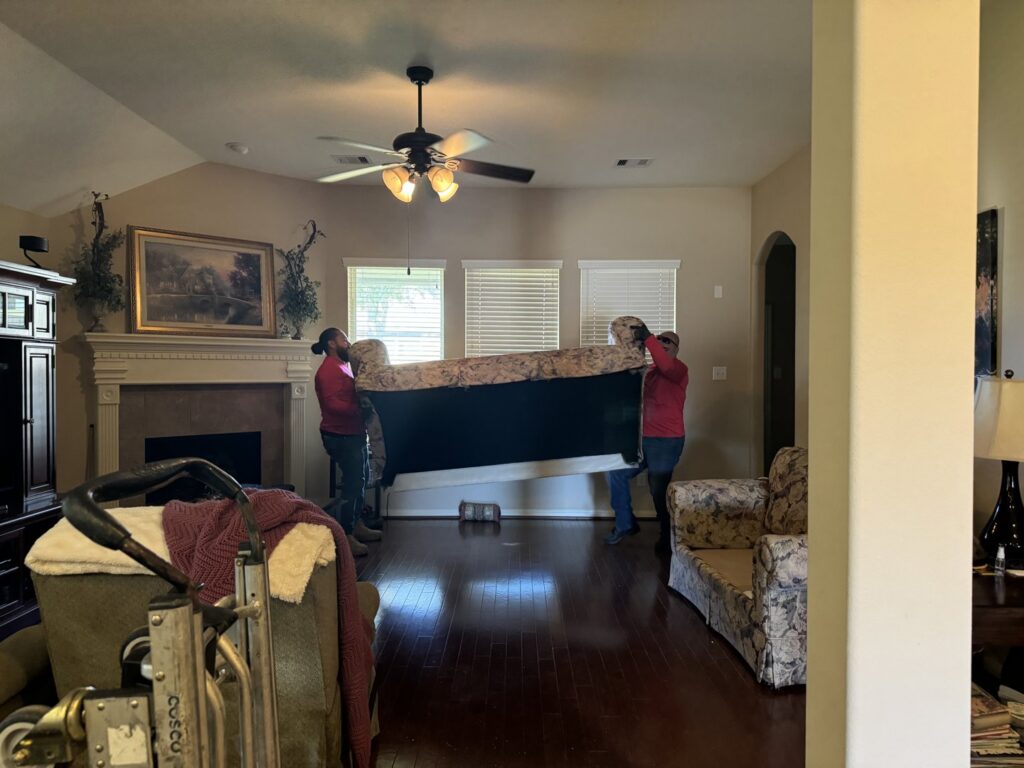 Speedy Junk Removal & recycling workers carefully removing a large sofa from a client's home in Houston, TX.