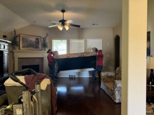 Speedy Junk Removal & recycling workers carefully removing a large sofa from a client's home in Houston, TX.