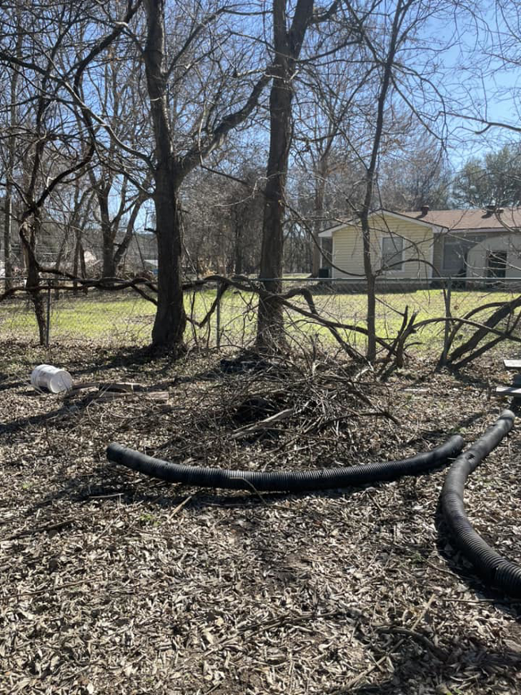 A pile of yard debris, black corrugated pipes, and a white bucket in a yard for removal by Just Junk It Disposal in Jonesborough, TN.