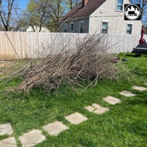 A large pile of tree branches and yard debris in a backyard, ready for removal by We Haul It Cleaning Service LLC in Canal Winchester, OH.
