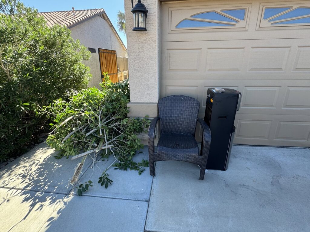Yard waste, an old patio chair, and a cabinet placed outside a garage for J & R Junk Removal in Phoenix, AZ.