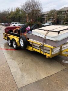 A yellow trailer filled with mattresses and various household junk items, collected by Perez Junk Removal in Anaheim, CA.